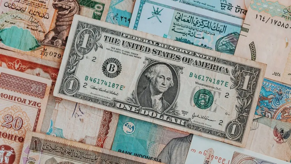 Banknotes from several countries overlapping on a flat surface.